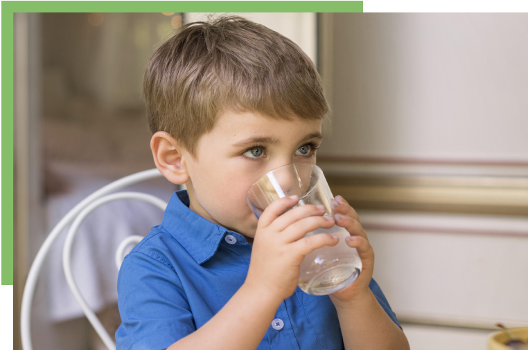 A young boy drinking water from a glass.